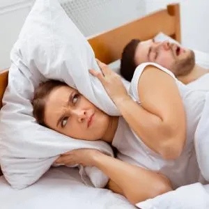 Woman covering ears while partner snores
