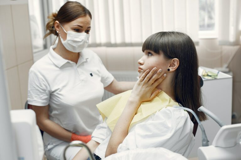Woman pressing one hand to a single side of her face in pain