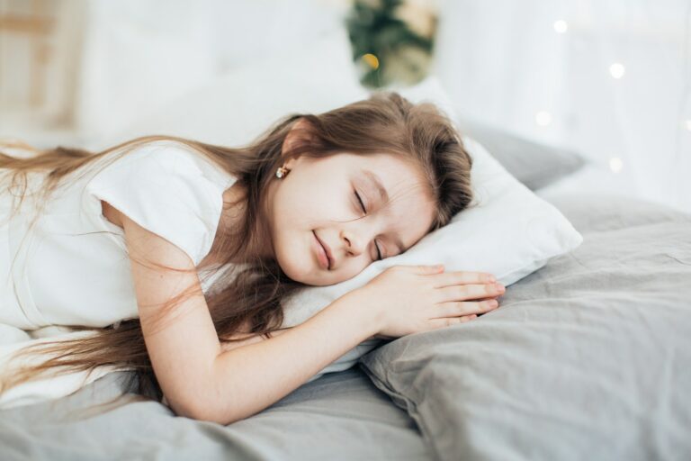 Young girl asleep on a pillow with her hands tucked under her cheek