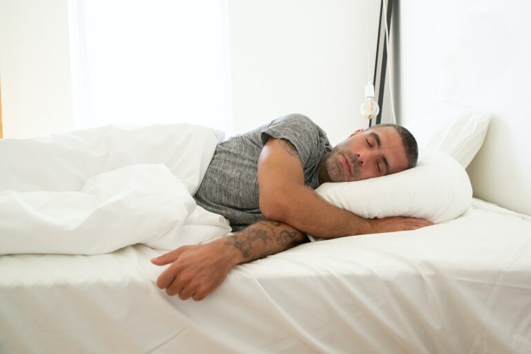 Bearded man asleep on his side in white bedding