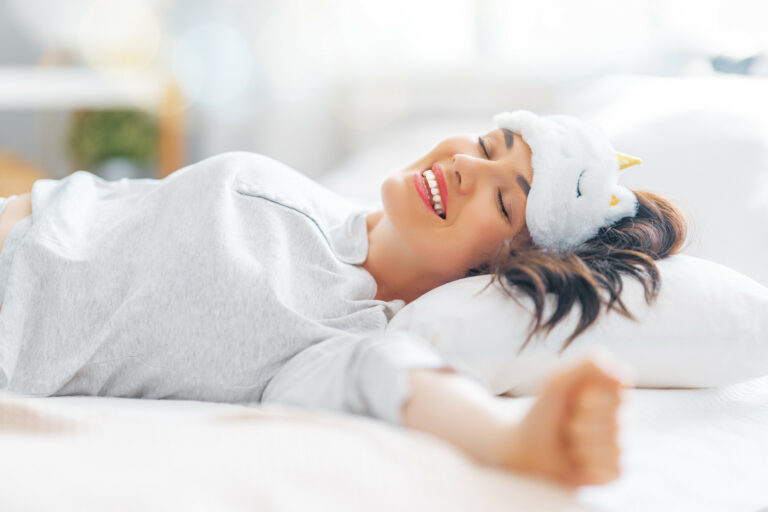 Woman smiling in her sleep, a sleep mask pushed up on her forehead