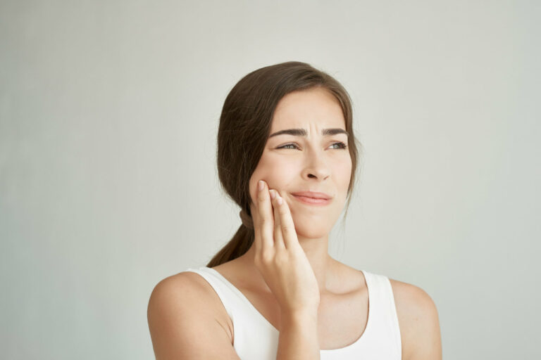 Woman holding one hand flat against her cheek and jaw in discomfort