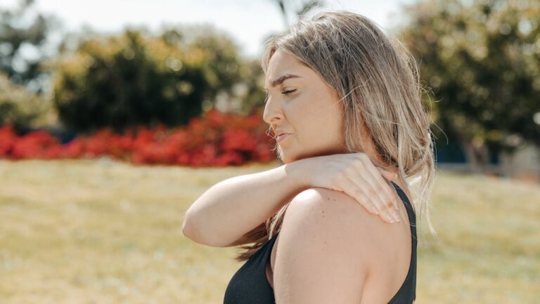 Woman rubbing the base of her neck where it meets her shoulder