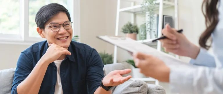 Patient talking with a clinician across a desk during a treatment consultation