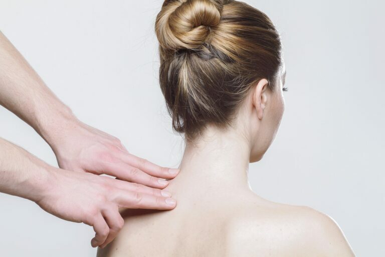 Therapist pressing two fingers into the side of a seated woman neck during treatment