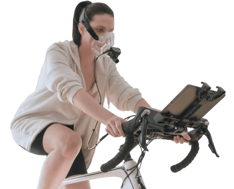 Woman on a stationary bike wearing a PNOĒ breath-analysis mask during a metabolic test